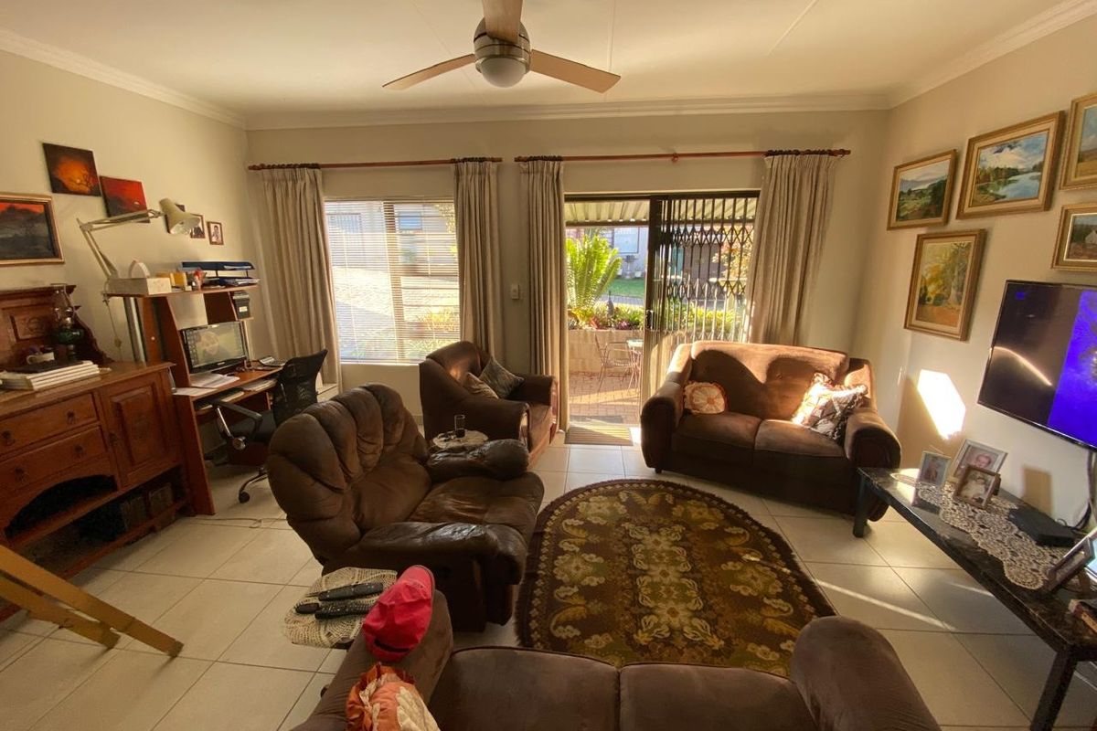 A comfortable living room featuring tiled flooring, a ceiling fan, and a sliding glass door providing direct access to an outdoor patio area.