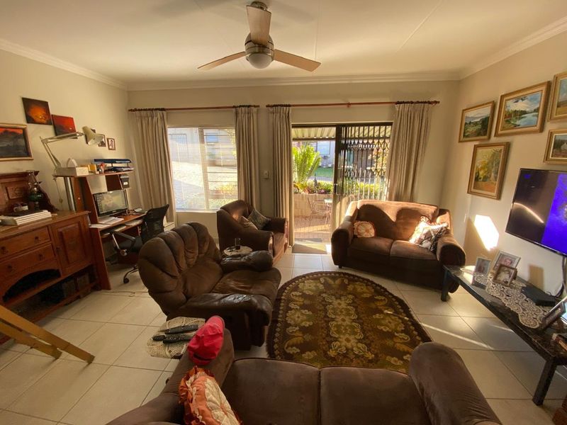 A comfortable living room featuring tiled flooring, a ceiling fan, and a sliding glass door providing direct access to an outdoor patio area.