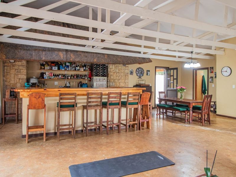 Spacious open-plan living area featuring a built-in bar with stone detailing, exposed timber roof trusses, and durable concrete flooring.