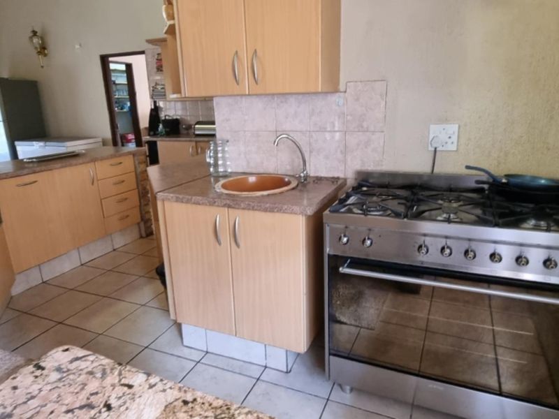 A functional kitchen featuring laminate cabinetry, granite countertops, a stainless steel gas stove, and tiled flooring with a practical layout.