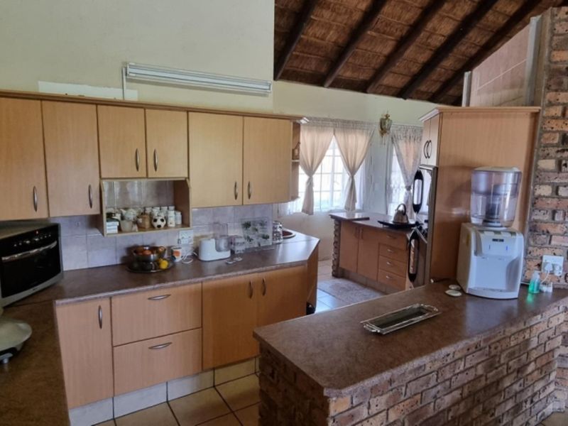 Open plan kitchen featuring laminated cabinetry, an exposed brick breakfast bar, and a distinctive thatched roof ceiling, creating a rustic and functional living space.