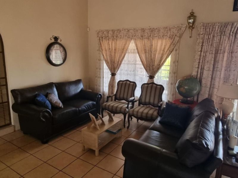 A comfortable living room featuring tiled flooring, an arched entryway, and large sliding glass doors that provide access to the outdoor patio area.