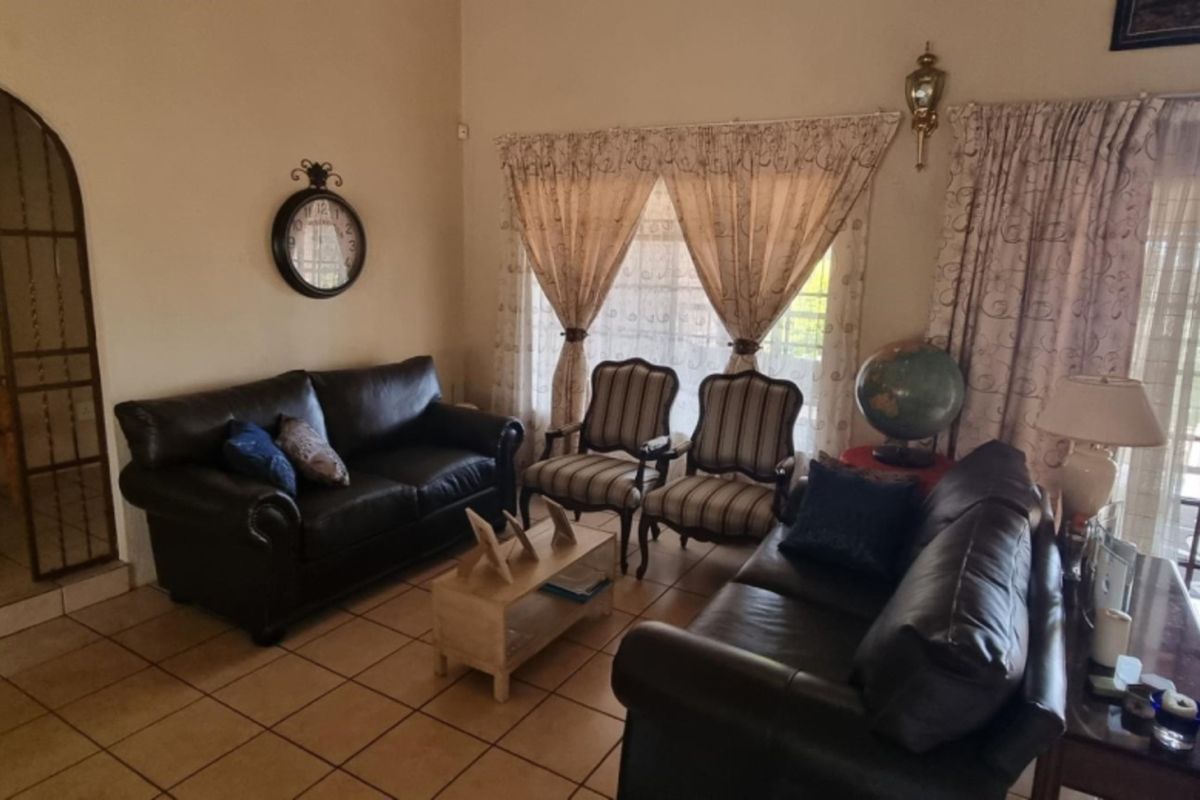 A comfortable living room featuring tiled flooring, an arched entryway, and large sliding glass doors that provide access to the outdoor patio area.