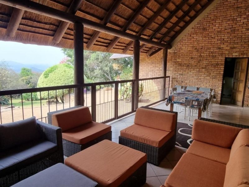 Spacious covered patio featuring a traditional thatched roof, exposed brickwork, and scenic views, ideal for outdoor entertaining.
