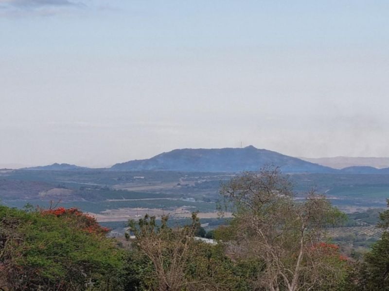 A scenic landscape view overlooking rolling hills and distant mountains, showcasing the natural beauty of the surrounding small holding area.