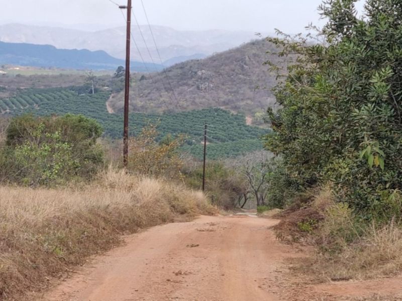 A scenic view of a dirt access road leading through the small holding, featuring rolling hills and mountain vistas in the background.