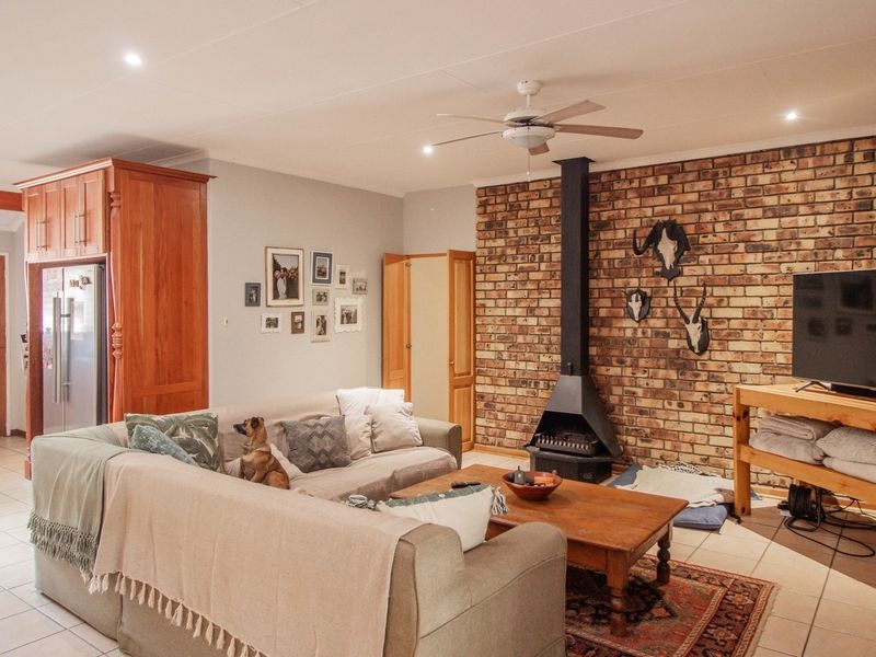 Spacious open-plan living area featuring an exposed brick wall with a built-in fireplace, tiled flooring, and integrated cabinetry.