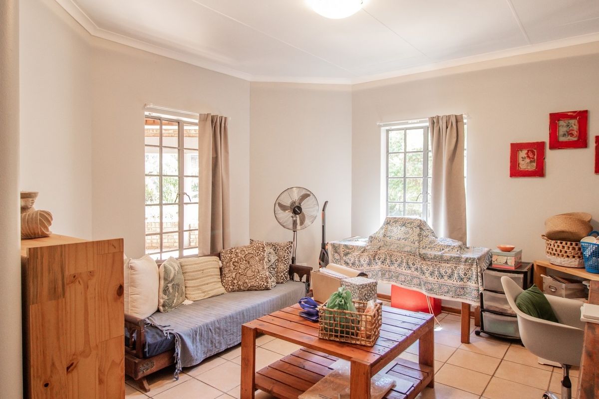 A bright living room featuring tiled flooring, coved ceilings, and large grid-pane windows that provide ample natural light.