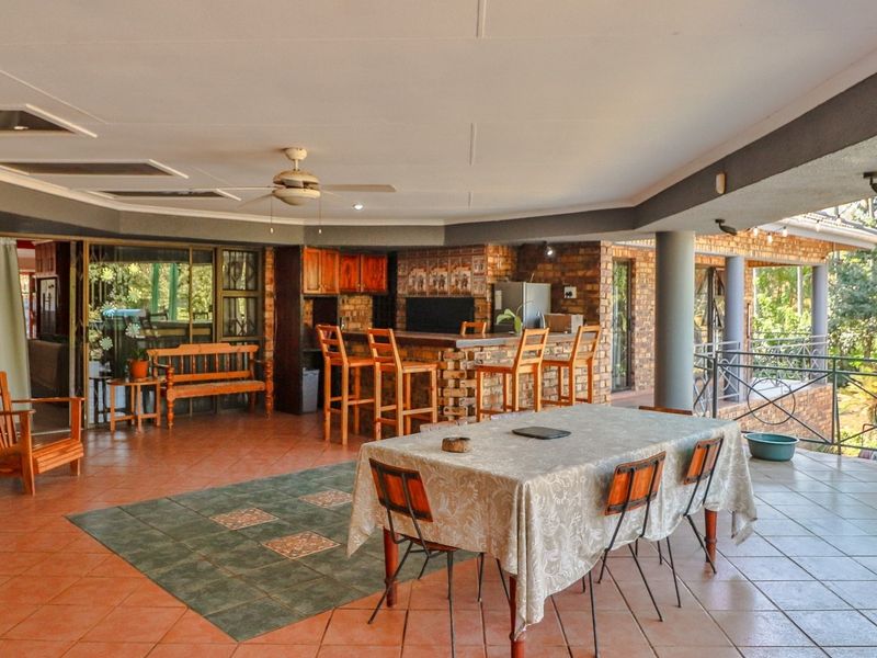 Spacious covered patio featuring a built-in bar, tiled flooring, and exposed brickwork, ideal for outdoor entertaining and dining.