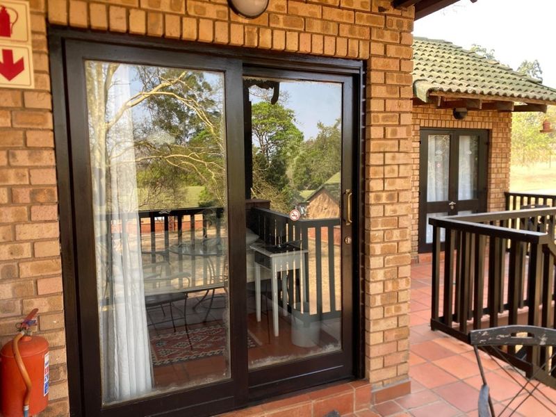 A covered balcony area featuring brick walls, tiled flooring, and sliding glass doors providing access to the interior.