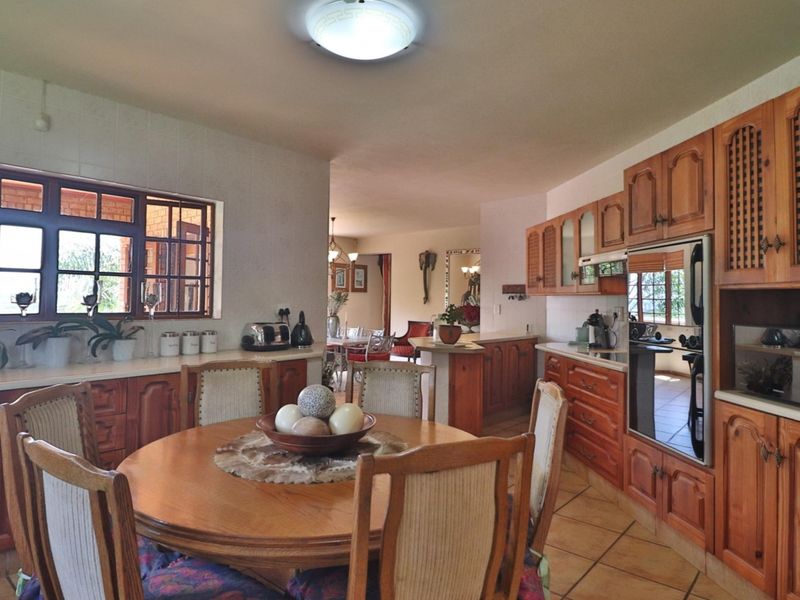 Open plan kitchen and dining area featuring traditional wooden cabinetry, built-in oven, and tiled flooring, offering a functional layout for family living.