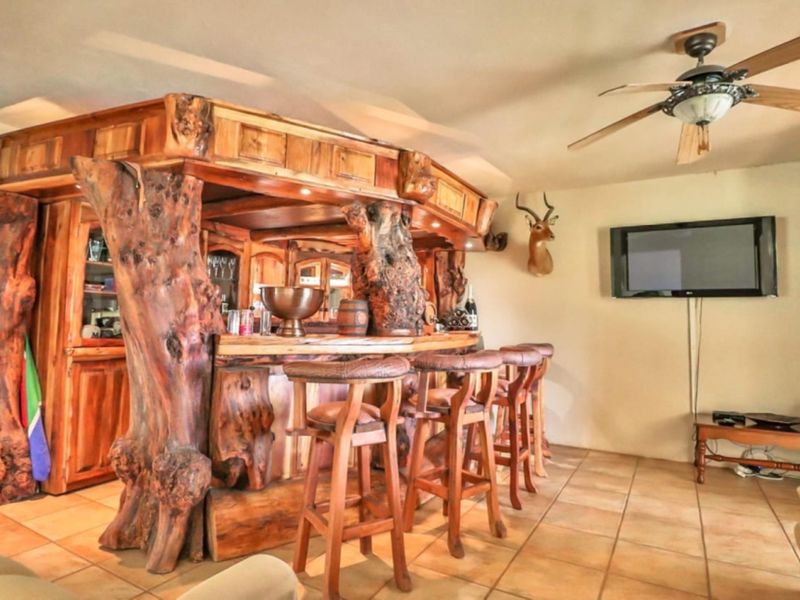 A rustic, custom-built wooden bar area featuring unique timber supports, tiled flooring, and a ceiling fan, creating a distinct entertainment space.