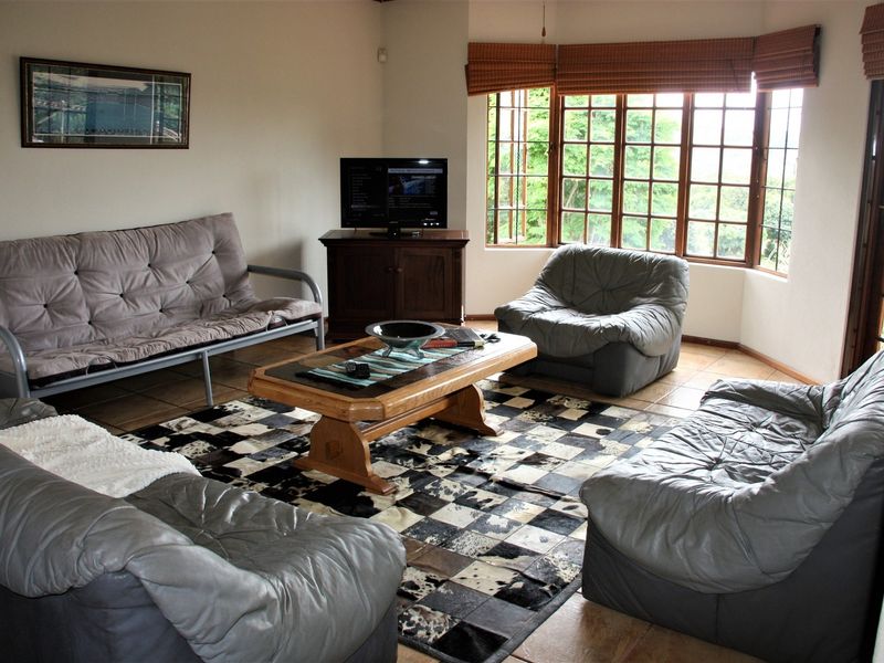 A comfortable living room featuring a large bay window with timber frames and tiled flooring, offering a bright and functional space.