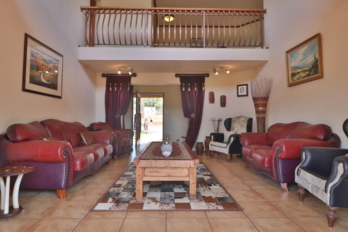 Spacious double-volume living room featuring tiled flooring, a mezzanine level with a metal balustrade, and direct access to the exterior entrance.