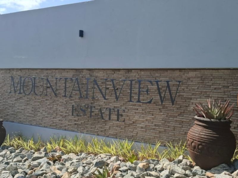 The entrance signage wall for Mountainview Estate, featuring stone cladding, integrated lighting, and a well-maintained landscaped rock garden.