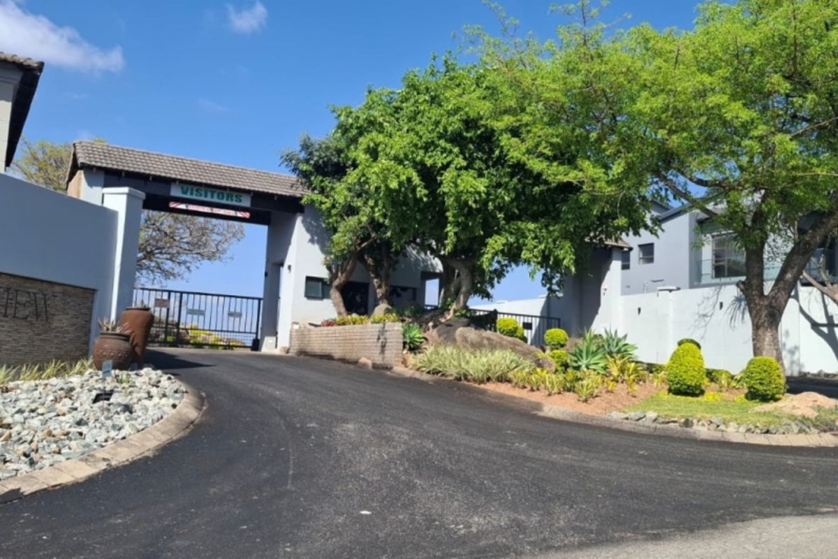 The entrance to Mountainview Estate featuring a secure gated access point, paved driveway, and well-maintained landscaped surroundings.