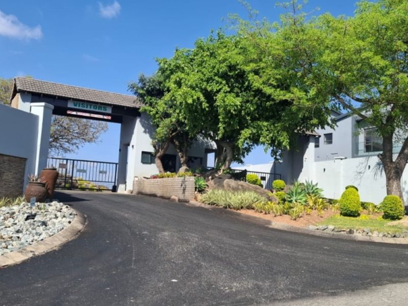 The entrance to Mountainview Estate featuring a secure gated access point, paved driveway, and well-maintained landscaped surroundings.