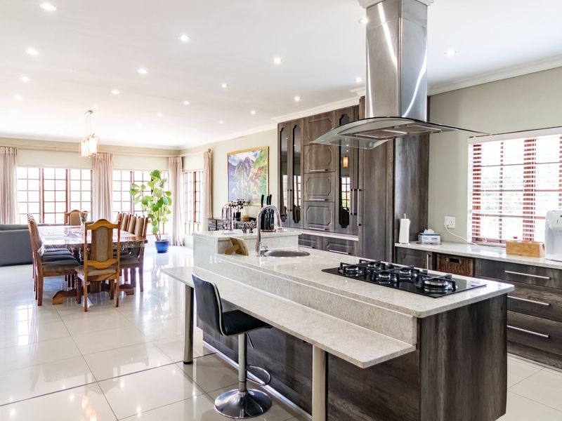 Spacious open-plan kitchen and dining area featuring a modern kitchen island with gas hob, sleek cabinetry, and polished tiled flooring throughout.