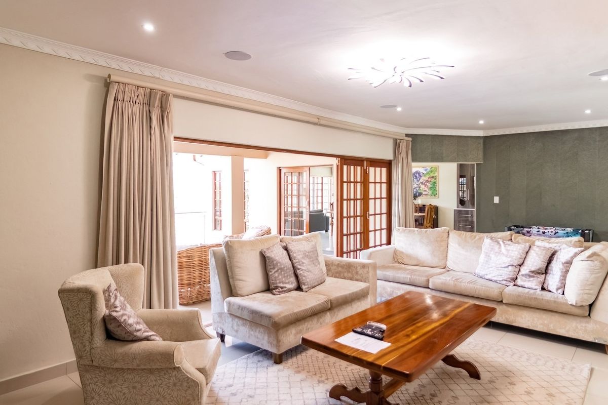 Spacious living room featuring recessed downlights, decorative crown molding, and large wooden sliding doors that open to an outdoor patio area.