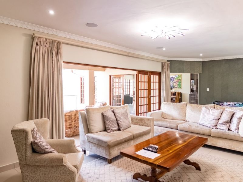 Spacious living room featuring recessed downlights, decorative crown molding, and large wooden sliding doors that open to an outdoor patio area.