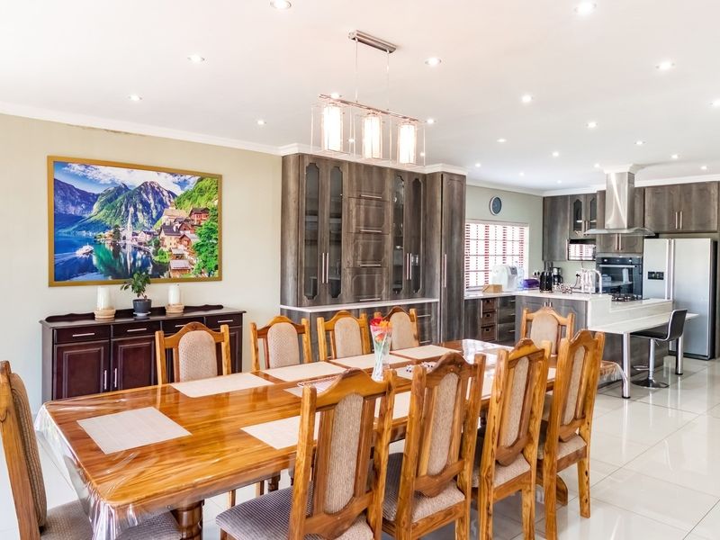 Spacious open-plan dining and kitchen area featuring modern built-in cabinetry, a central kitchen island, recessed lighting, and polished tiled flooring throughout.