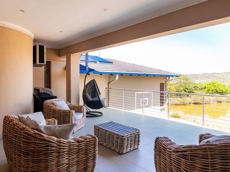 A spacious covered patio featuring tiled flooring and a stainless steel balustrade, offering an open view of the surrounding landscape.