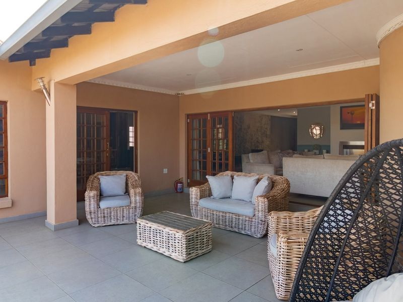 A spacious covered patio featuring tiled flooring and large timber-framed glass sliding doors that provide seamless access to the interior living area.