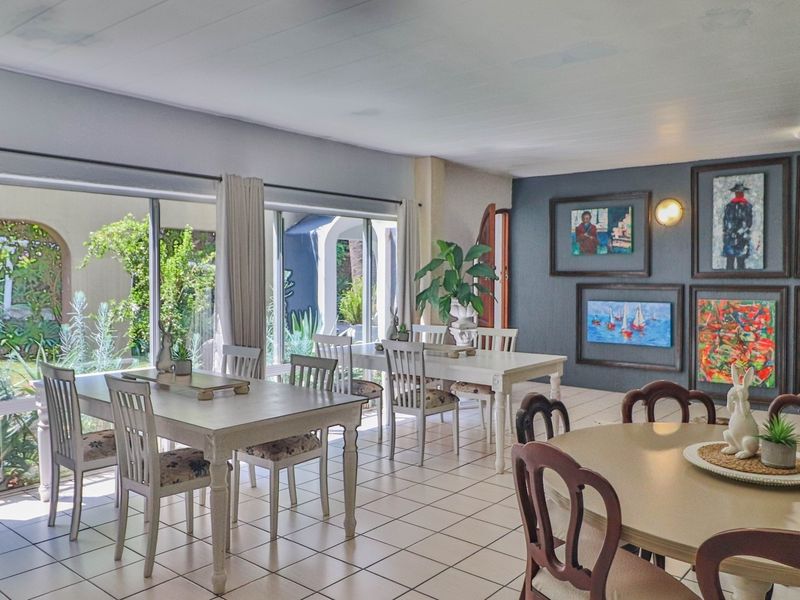 Spacious open-plan dining area featuring tiled flooring, large sliding glass doors providing garden access, and a prominent dark-toned accent wall.