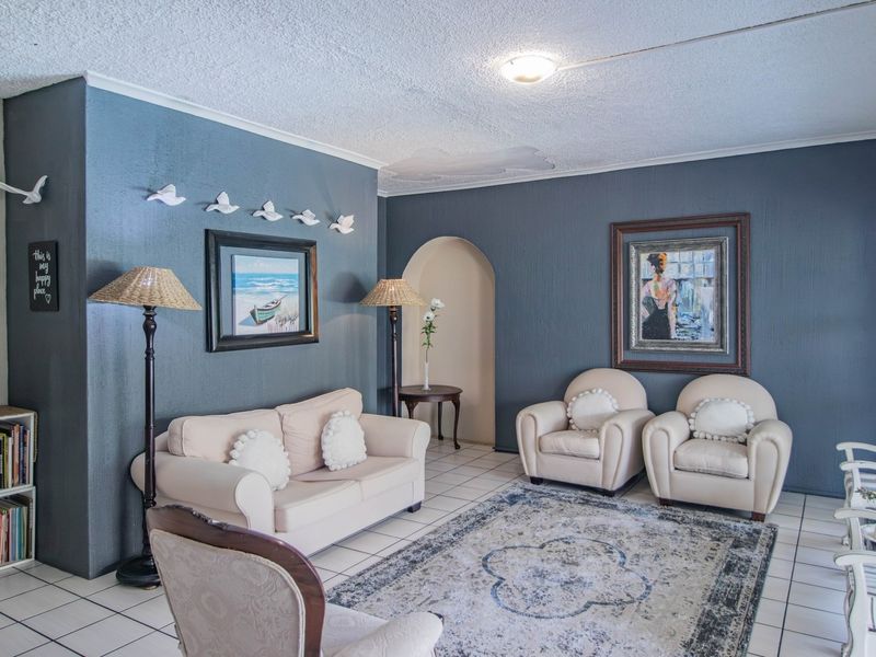 A living room featuring tiled flooring, an arched doorway, and a sliding glass door, with visible water damage on the ceiling.