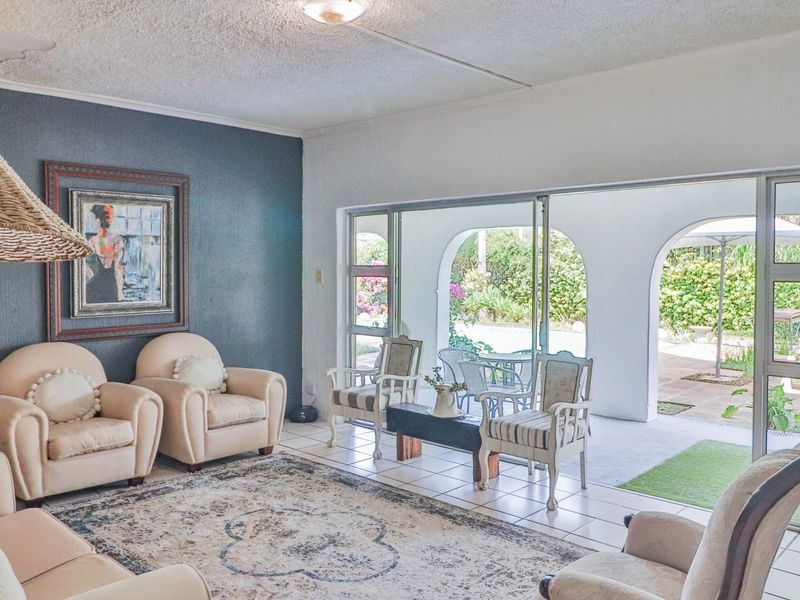 Spacious living room featuring large sliding glass doors that open onto a covered patio, with tiled flooring and a textured ceiling.