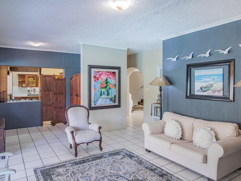 Spacious living area featuring tiled flooring, a decorative archway, and a convenient pass-through window connecting to the kitchen space.