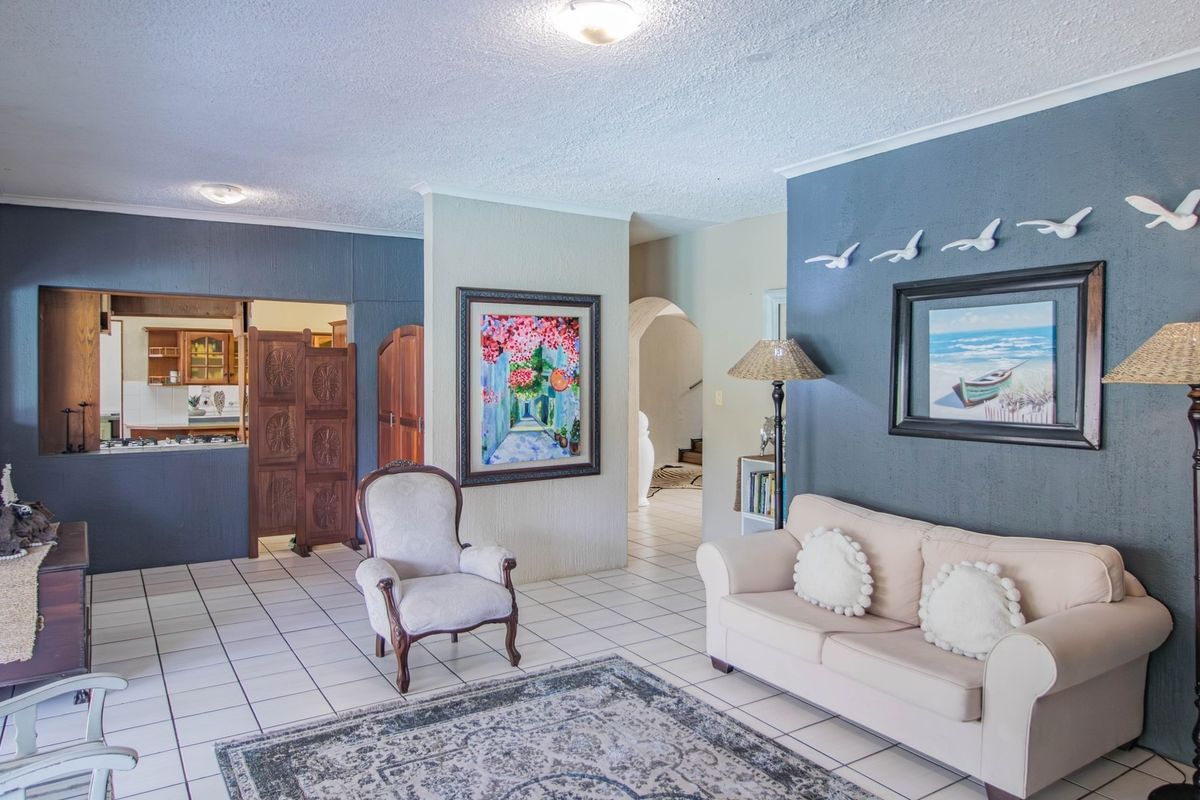 Spacious living area featuring tiled flooring, a decorative archway, and a convenient pass-through window connecting to the kitchen space.