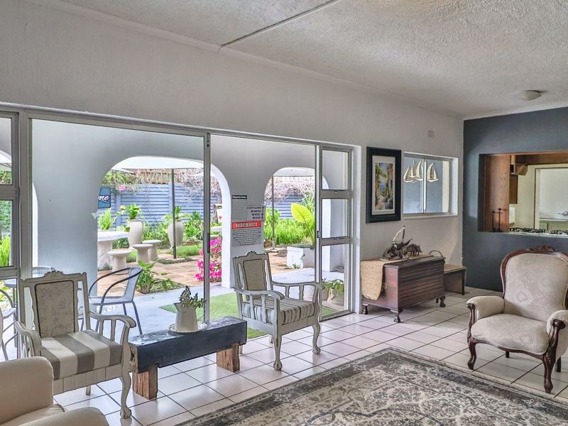 Open-plan living area featuring tiled floors, a pass-through window to the kitchen, and large sliding doors opening onto a covered patio.