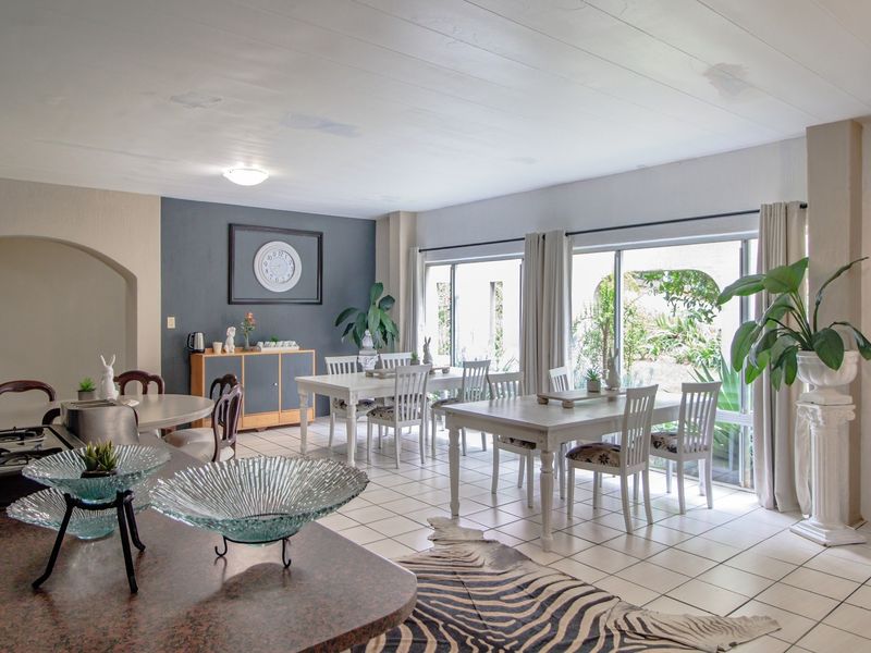 Spacious open-plan living and dining area featuring tiled flooring, large sliding glass doors providing garden access, and a functional kitchen counter space.