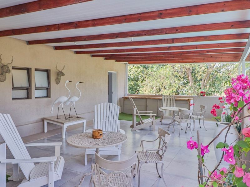 A spacious covered patio featuring a timber beam ceiling, tiled flooring, and a built-in counter, ideal for outdoor entertaining and relaxation.
