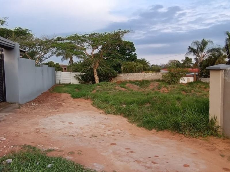 A vacant residential plot featuring a perimeter wall, sliding gate, and security fencing, providing a secure foundation for future development.