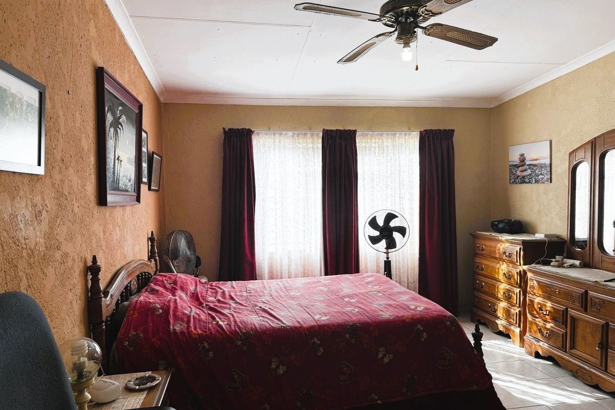 A bedroom featuring tiled flooring, a ceiling fan, and textured walls, offering a dated aesthetic that could benefit from modern updates.