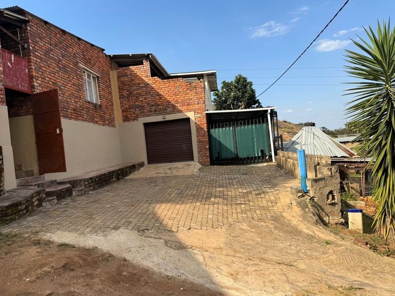 Front exterior view of the property featuring a brick facade, paved driveway, and a secure roller garage door.