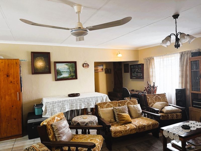 A spacious living room featuring tiled flooring, a ceiling fan, and neutral wall finishes, offering a comfortable and functional layout.