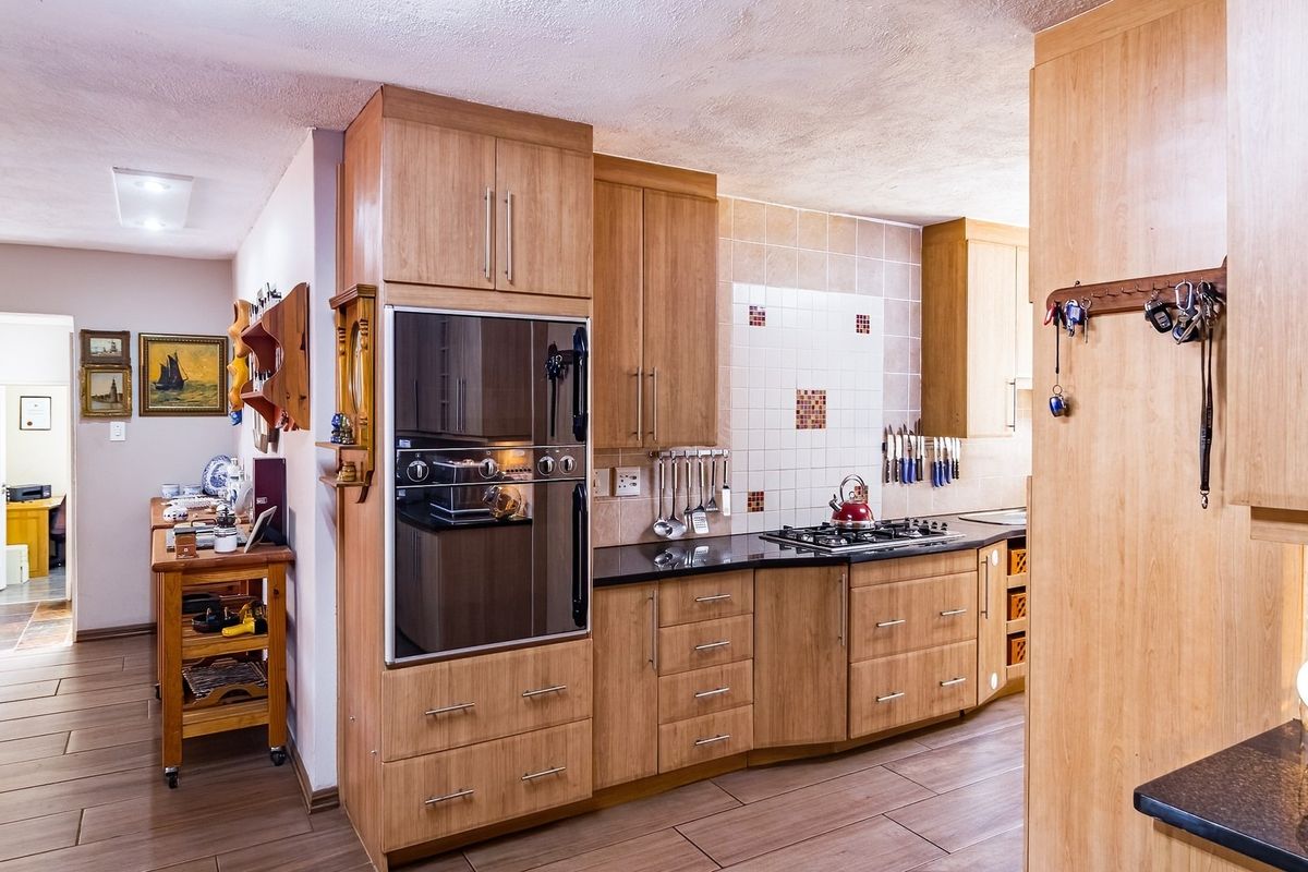 A functional kitchen featuring wood-look cabinetry, granite countertops, a built-in oven, and a gas hob with a tiled backsplash.