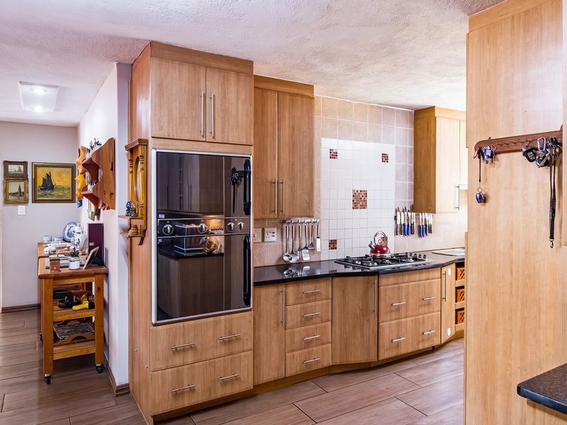 A functional kitchen featuring wood-look cabinetry, granite countertops, a built-in oven, and a gas hob with a tiled backsplash.