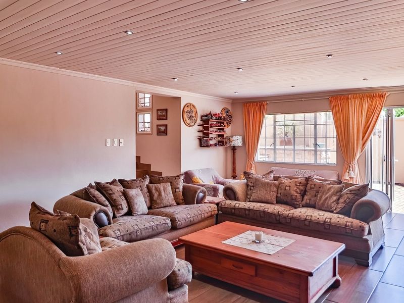 Spacious living room featuring timber-clad ceilings, recessed lighting, and large sliding doors providing direct access to the outdoor patio area.
