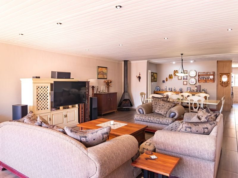 Spacious open-plan living and dining area featuring tiled flooring, a modern freestanding fireplace, and recessed downlighting throughout the space.