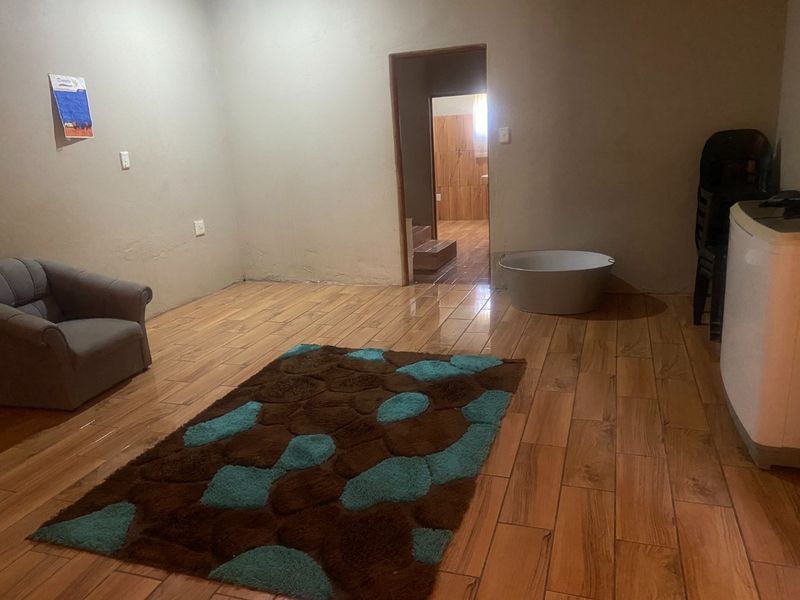 A sparsely furnished living area featuring wood-look tile flooring and neutral wall finishes, providing a blank canvas for interior design.