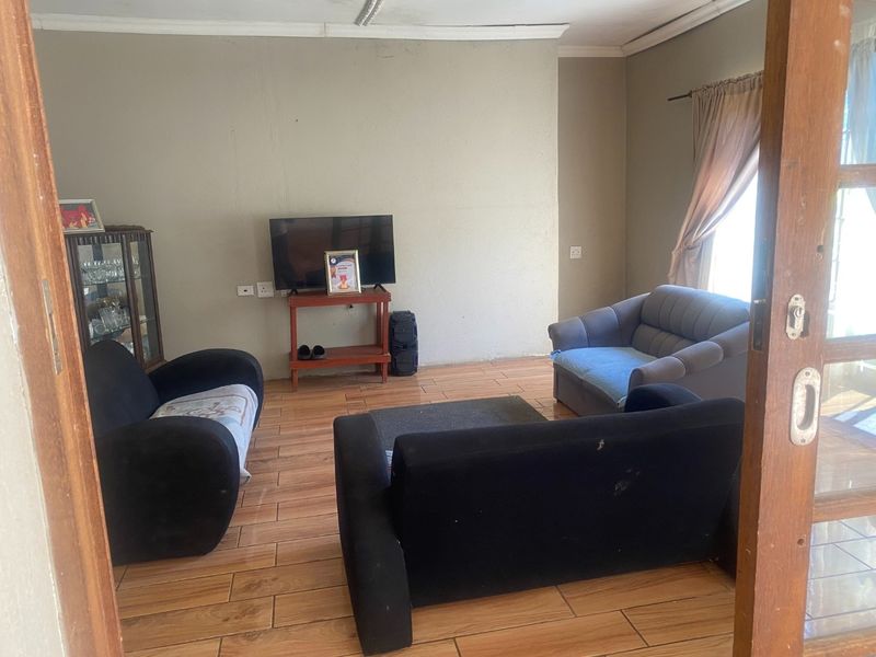A living room featuring tiled flooring and coved ceiling details, viewed through a timber door frame.