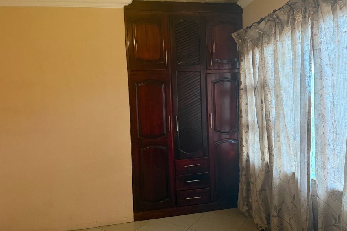 A bedroom featuring a large built-in wooden wardrobe, tiled flooring, and decorative ceiling finishes.