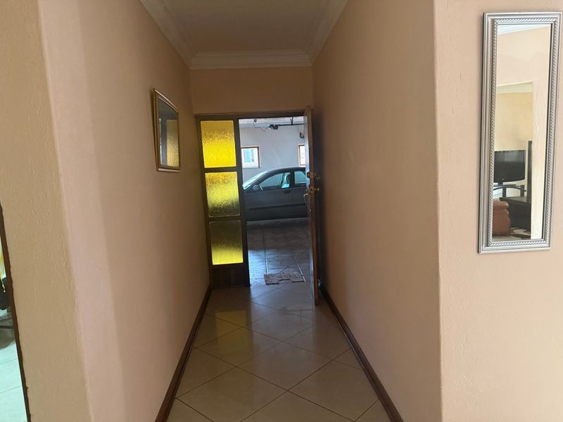 A neutral-toned hallway featuring tiled flooring and coved ceilings, providing a clean transition space between the interior and the garage area.