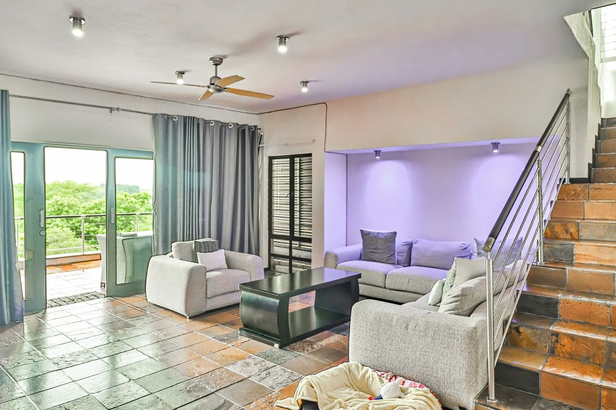 Spacious living room featuring tiled flooring, a staircase with metal railing, recessed lighting, and direct access to an outdoor balcony through sliding glass doors.