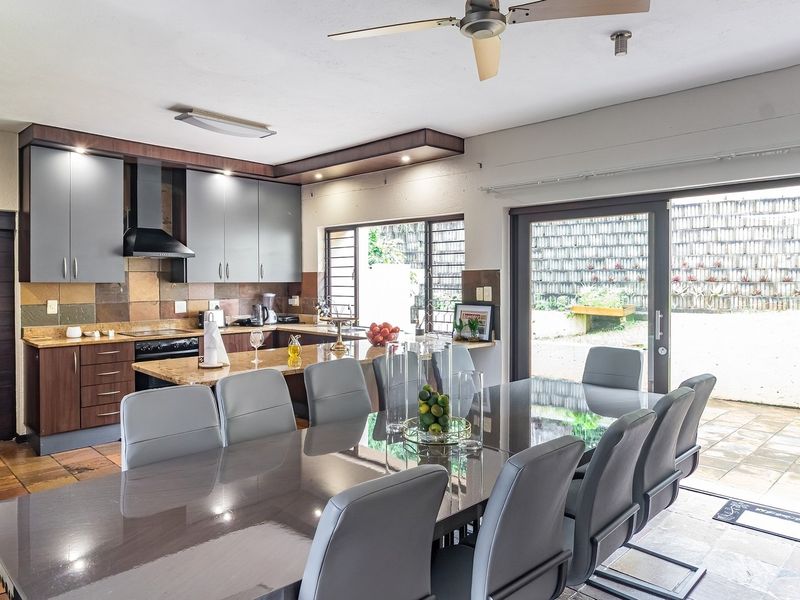 Spacious open-plan kitchen and dining area featuring modern cabinetry, granite countertops, and large sliding doors providing seamless access to the outdoor patio.