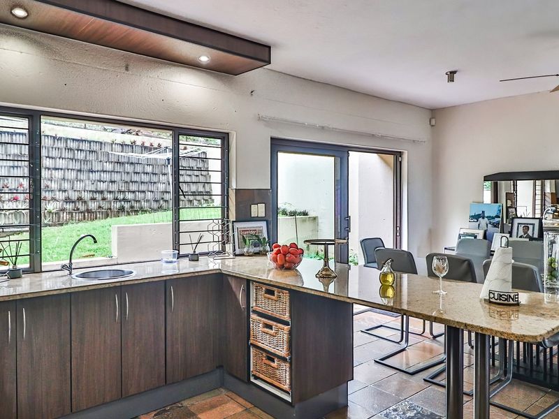 Open-plan kitchen and dining area featuring granite countertops, dark wood cabinetry, and direct access to the rear garden through sliding glass doors.